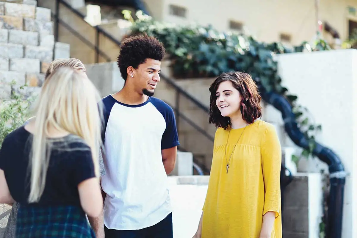 Jeunes adultes échangeant ensemble avec le sourire
